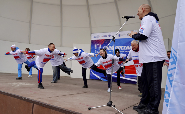 Зарядка с чемпионами: в упражнении «ласточка» на сцене в парке солирует Евгений Подгорный, российский гимнаст, олимпийский чемпион, заслуженный мастер спорта РФ. Фото: пресс-служба НРО партии «Единая Россия»